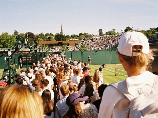 A crowd watching a tennis match from the stands