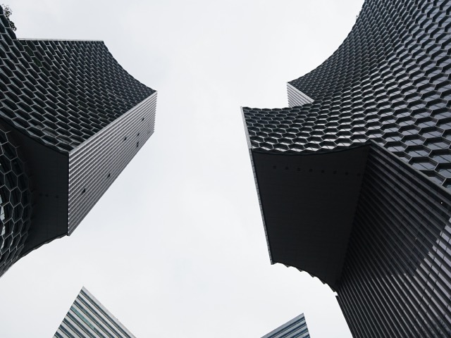 Geometric black towers rising into a white sky