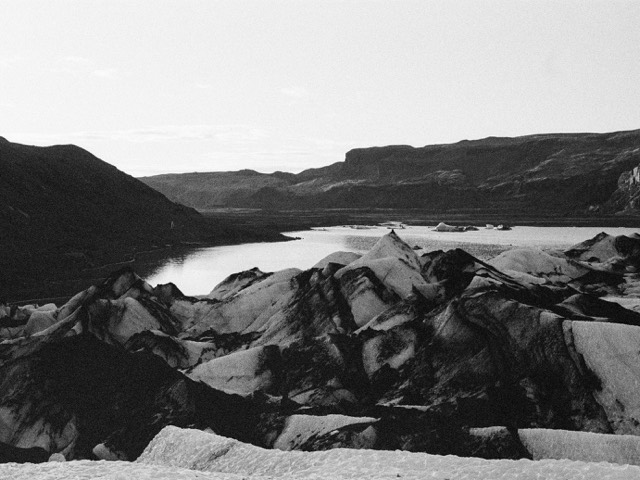 A black-and-white mountain river winding through dark rock