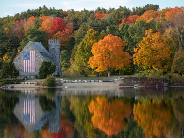 A lakeside house surrounded by autumn trees