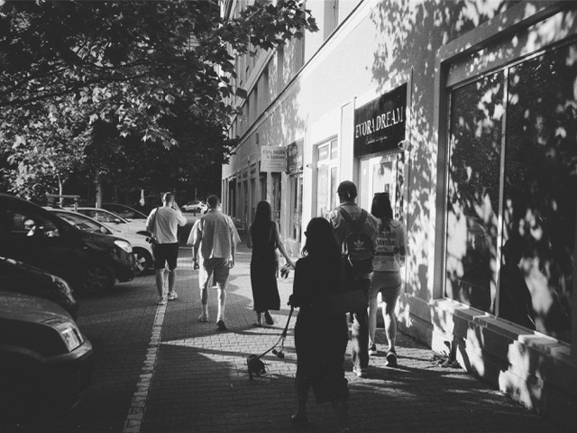 Pedestrians walking through a high-contrast black-and-white street scene